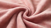 Soft pink fleece fabric with twisted spiral pattern showing cozy textile texture for clothing design, blankets, winter apparel and home decor projects.