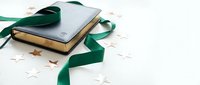 Elegant book with green ribbon and white paper stars on clean background for holiday gifting, education, literature and festive celebration concepts.