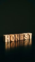 Wooden letter blocks spelling HONEST on dark reflective surface with warm lighting for business ethics and integrity concepts.