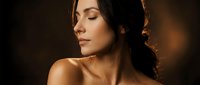 Young brunette woman with closed eyes in golden warm lighting showcasing natural beauty and skincare routine for wellness and spa treatments.