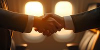Business handshake between two professionals in suits against warm glowing lights background, symbolizing partnership agreement and successful deal closing.