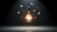 Glowing light bulb surrounded by business icons on dark background representing innovation, creativity and entrepreneurship concepts for presentations.