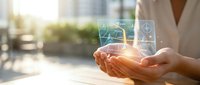 Hands holding glowing digital financial charts and graphs with sunlight, representing data analysis, investment growth, and business analytics technology.