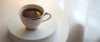 Cup of black tea or coffee on white round table with soft natural light and blurred background, suitable for beverage, lifestyle and hospitality design projects.
