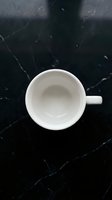 Empty white ceramic mug on black marble surface, overhead view. Minimalist tabletop styling for beverage, coffee, tea, and kitchen product mockups.