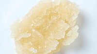 Crystalline rock candy or sugar crystal formation with pale yellow translucent chunks on white background, suitable for confectionery, food, and culinary content.