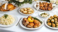 Festive dinner table with roasted chicken, mashed potatoes, mushrooms and various side dishes served on white plates. Elegant holiday meal setting.