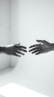 Two hands reaching toward each other in black and white, symbolizing connection, help, support and human relationships for emotional concepts.