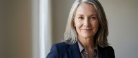 Mature woman with long gray hair wearing dark blazer, professional portrait for business, corporate, and leadership concepts.