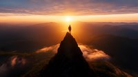 Silhouette of person standing on mountain peak at dramatic sunset, surrounded by clouds and mountain ranges, symbolizing achievement and freedom.
