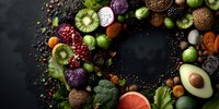 Colorful superfood wreath arrangement with fresh fruits, vegetables, nuts and seeds on dark background for healthy eating and nutrition concepts.