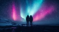 Silhouette of couple watching vibrant aurora borealis display with pink and turquoise colors dancing across starry night sky over snowy winter landscape.
