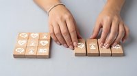 Female hands arranging wooden blocks with customer service icons on gray surface for business communication and support concept.