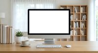 Modern home office workspace with blank computer monitor screen on wooden desk ready for mockup design presentations and digital content display.