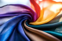 Abstract swirling fabric with vibrant rainbow colors creating dynamic spiral motion for modern design backgrounds and creative projects.