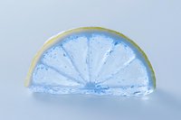 Frozen lemon slice encased in clear blue ice on a light background, showcasing fresh citrus texture for food and beverage concepts.