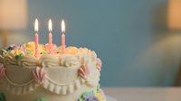 Birthday cake with lit candles and colorful frosting flowers for celebration party dessert bakery sweet treat special occasion festive moment.