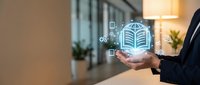 Businessman holding glowing digital building icon with connected network symbols in modern office environment for smart city and real estate technology concepts.
