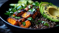 Nutritious quinoa bowl with roasted sweet potato cubes, fresh avocado slices, mixed greens and herbs for healthy meal preparation and clean eating lifestyle.