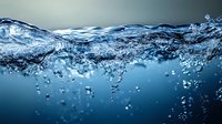 Dynamic underwater wave with rising air bubbles captured in crystal clear blue water, showing natural fluid motion and turbulent surface movement. Suitable for environmental themes.
