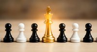Golden chess king piece standing out among black and white pawns on wooden board representing leadership, strategy and business success.