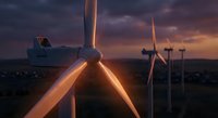 Wind turbines generating renewable energy at sunset with dramatic purple and orange sky creating sustainable power for clean electricity production.