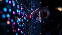 Hand touching glowing digital interface with colorful bokeh lights in dark background, representing technology interaction and data visualization concept.