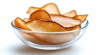 Crispy homemade apple chips in transparent glass bowl, healthy snack alternative to potato chips for clean eating and natural desserts.