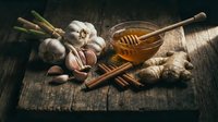 Garlic, ginger root, and honey with wooden dipper arranged on rustic wooden surface for cooking, natural remedies, and wellness content.
