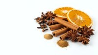 Aromatic winter spices with dried orange slices, cinnamon sticks, star anise and cloves isolated on white background for seasonal cooking and baking.
