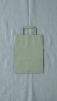 Blank sage green paper shopping bag with flat handles isolated on neutral linen background, ready for branding, packaging design, and retail mockup projects.