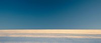 Vast frozen landscape with golden horizon line under clear blue sky, suitable for winter backgrounds and nature concepts.
