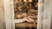 Cozy winter morning scene with hands holding warm coffee cup, soft sweater, books and blanket creating hygge atmosphere for relaxation and comfort.