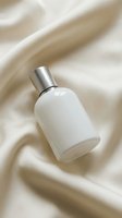 White perfume bottle with silver cap on cream silk fabric background for luxury cosmetics branding and beauty product photography.