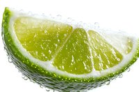 Fresh lime wedge with water drops on white background, bright green citrus slice showing juicy pulp texture and natural moisture for cocktail garnish.