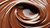 Swirling melted chocolate creates smooth spiral texture with glossy surface and rich brown tones, showcasing luxurious dessert ingredient in macro photography.