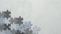 Gray jigsaw puzzle pieces scattered on textured white background with copy space for business strategy and problem solving concepts.