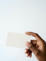 Closeup of male hand with medium skin tone holding blank cream business card against white background, suitable for branding, corporate identity, and stationery mockup designs.