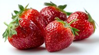 Fresh ripe strawberries with green leaves on white background, juicy red berries for healthy eating, desserts, and summer recipes.