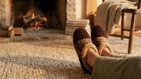 Cozy winter evening at home with feet in warm knitted socks by crackling fireplace creating comfortable relaxing atmosphere for cold weather comfort.
