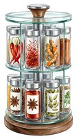 Rotating spice rack with glass jars containing red chili peppers, saffron threads, ginger root, cinnamon sticks, star anise, cardamom pods and herbs for kitchen storage and cooking.