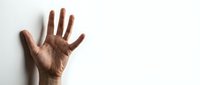Adult male hand with medium-dark skin tone raised in stop gesture against white background, suitable for communication, rejection, warning, and safety concepts.