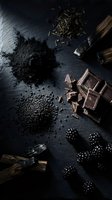 Dark chocolate pieces with activated charcoal powder and blackberries on slate surface for gourmet dessert and healthy food concepts.