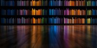 Colorful library bookshelves glowing in darkness create vibrant reflections on polished wooden floor, multicolored spines casting rainbow light pattern in panoramic view.