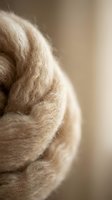 Soft beige wool yarn in cozy bundle with warm natural lighting for knitting crafts and textile projects.
