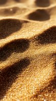 Macro shot of golden sand dunes with sparkling particles catching sunlight, creating dramatic shadows and textures for luxury and nature backgrounds.