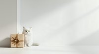 White fluffy cat sitting next to wrapped gift box with gold bow on white background, isolated for holiday greeting cards and seasonal marketing materials.