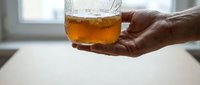 Close-up of a hand holding a glass of amber liquid with ice cubes, suitable for beverage, lifestyle, and hospitality design projects.