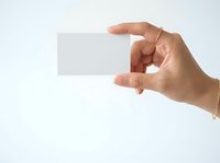 Hand holding blank white business card or paper mockup against neutral background for branding and corporate identity design projects.