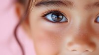 Close up macro shot of Asian female eye with natural makeup, soft pink background, showing clear skin texture and brown iris detail. Perfect for beauty and cosmetic advertising.